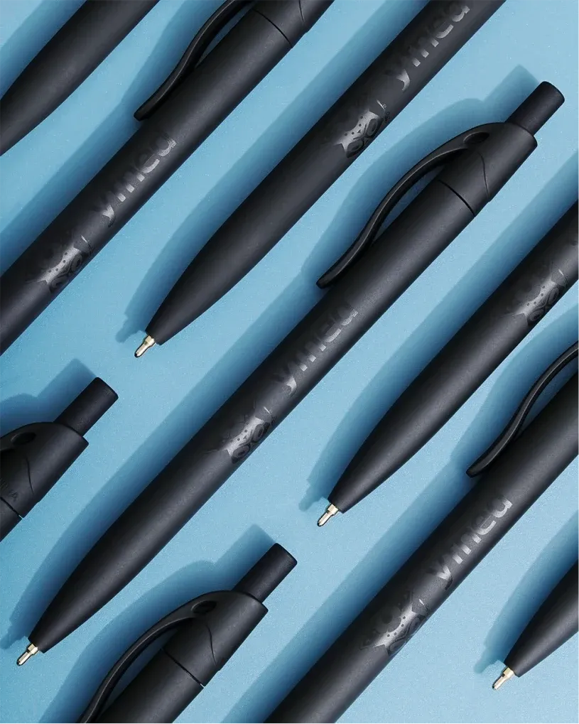 Matte black YFNED pens laid diagonally on a bright blue background.