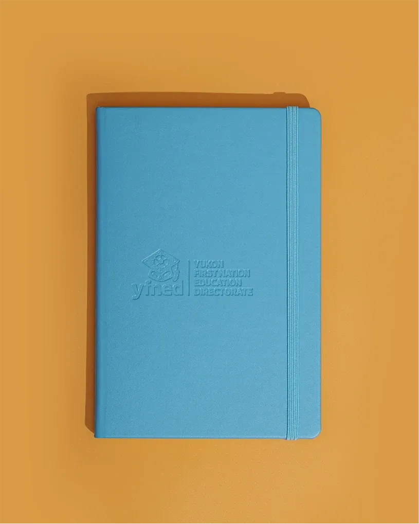 Light blue notebook with an elastic band and an embossed YFNED logo.